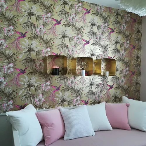 Detailreiche Wandgestaltung im Wohnzimmer mit einer hochwertigen Motivtapete (pinke Vögel und Palmenblätter auf goldenem Grund).